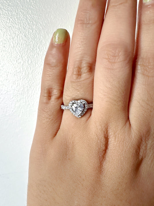 Close-up of a hand wearing an adjustable heart-shaped ring with premium-grade zirconia stones and a halo setting