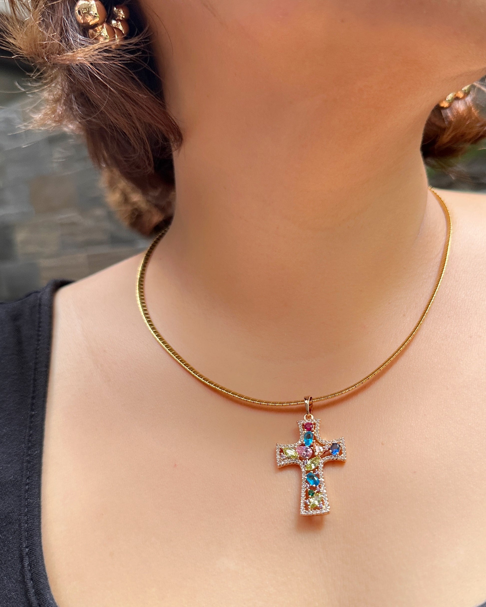 Close-up of radiant jewel-tone cross worn on model’s neck