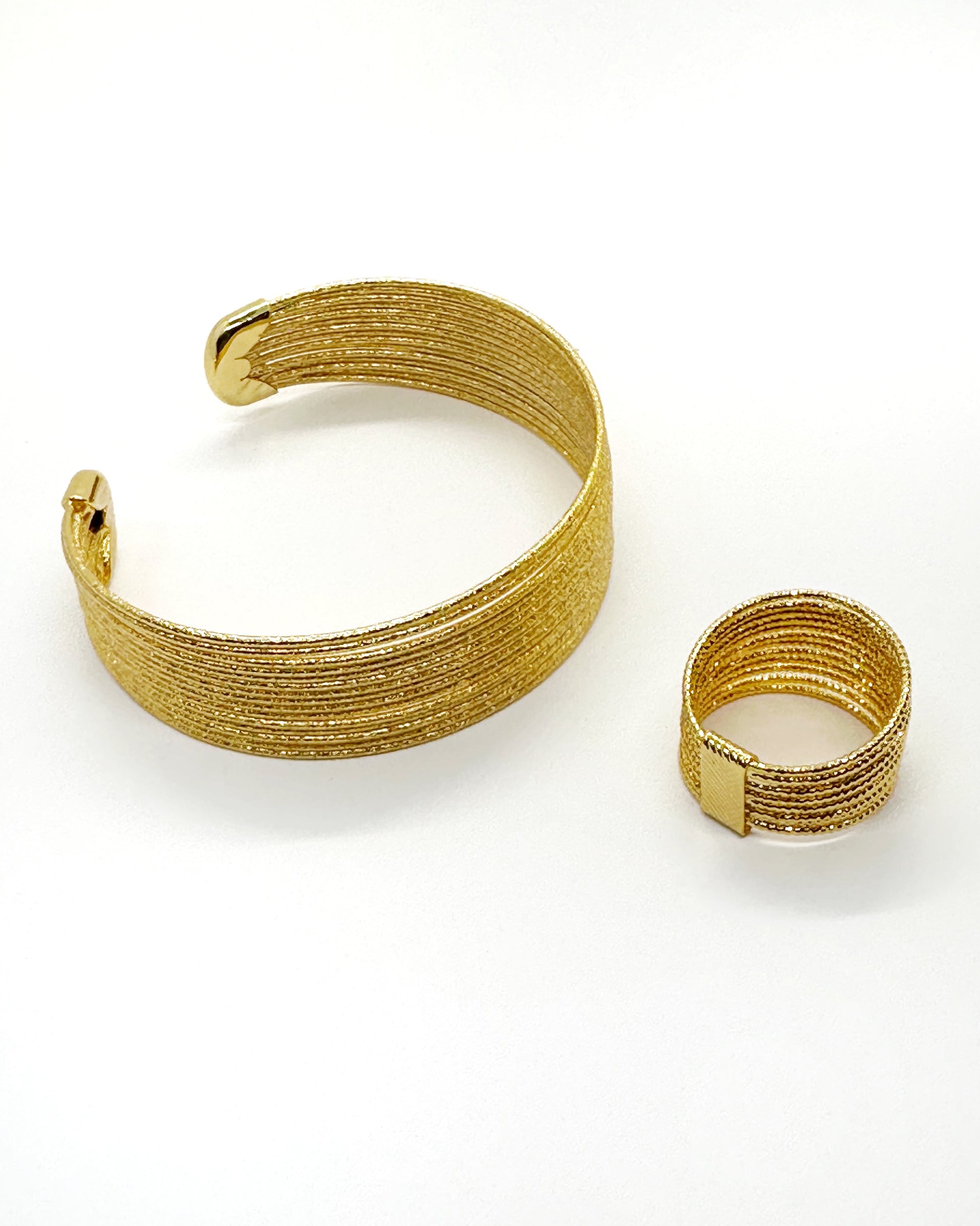 Wide gold cuff and matching textured gold ring set flatlay