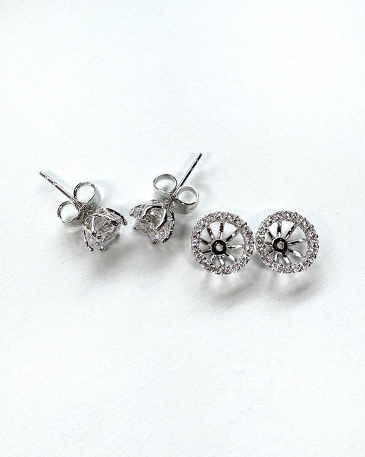 Flat lay of two pairs of silver halo stud earrings with premium-grade cubic zirconia stones on white background, showing both front and side views