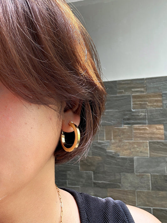 Gold-plated chunky hoop earrings styled with short hair and black top