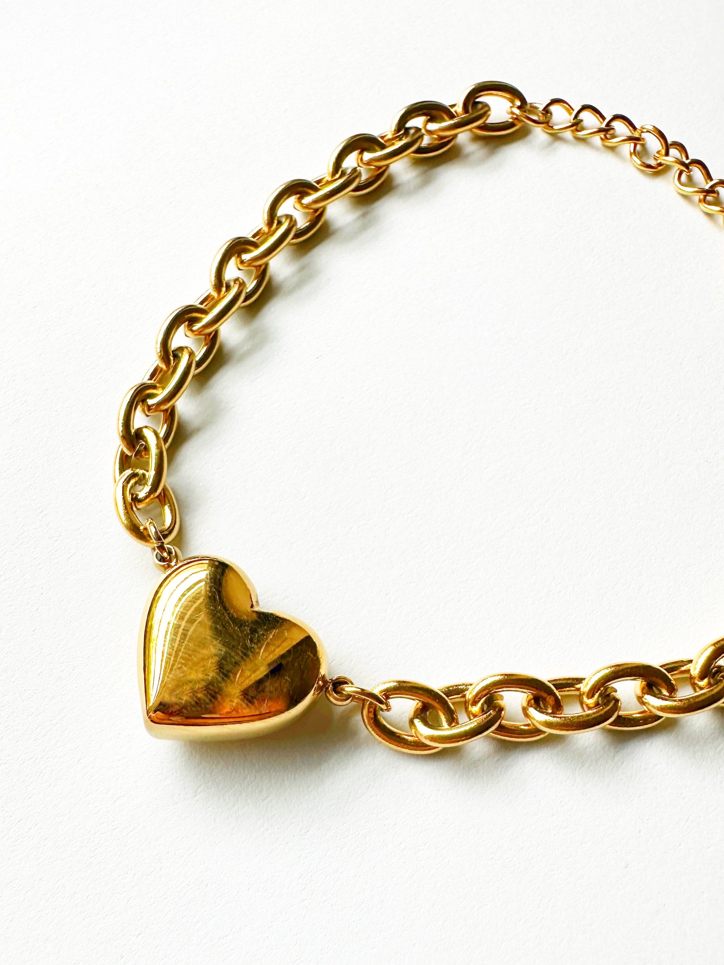 Close-up of gold-plated chunky heart chain bracelet with polished puffy heart charm