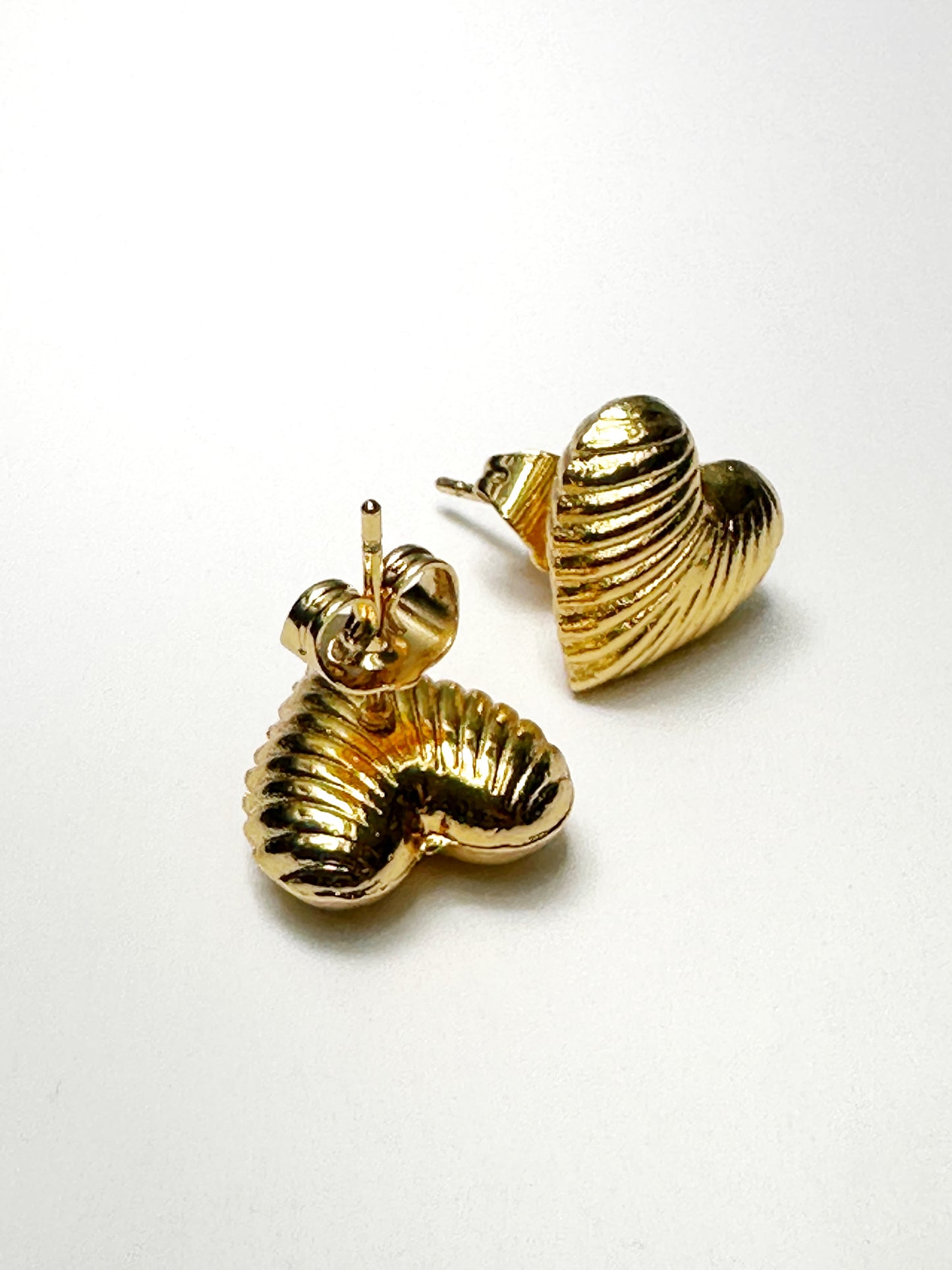 Angled view of ribbed heart earrings showcasing shine and texture detail