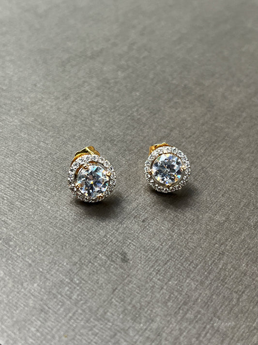 Close-up of Radiant Halo Stud Earrings with gold setting and CZ stones on a neutral gray background