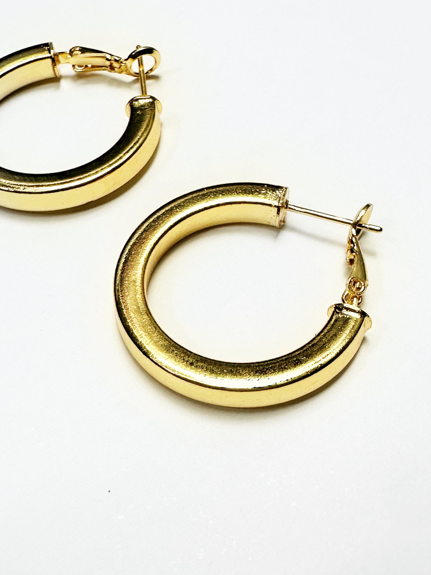 Close-up of thick, non-tarnish gold-plated hoop earrings with smooth curved shape