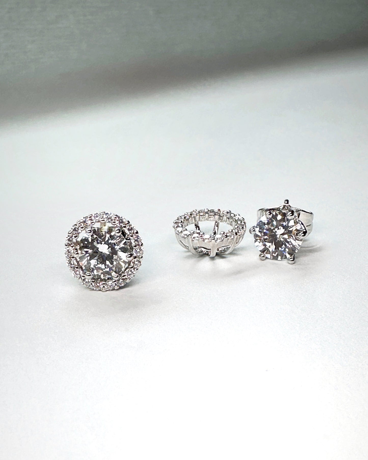 Three-piece layout showing silver halo earrings with removable jacket and solitaire stud core made of premium-grade cubic zirconia
