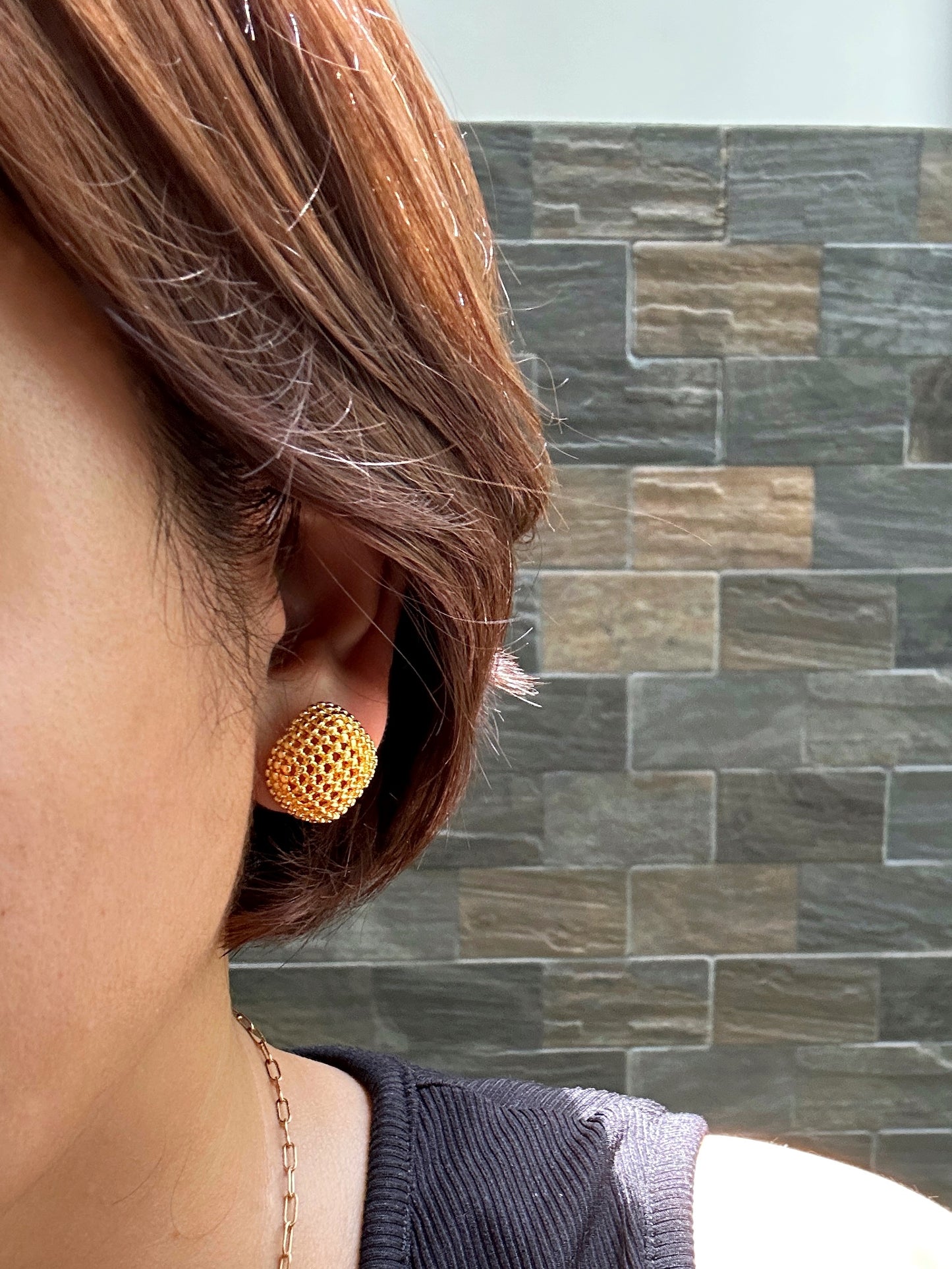 Model’s side profile showing large gold dome stud earring with mesh finish