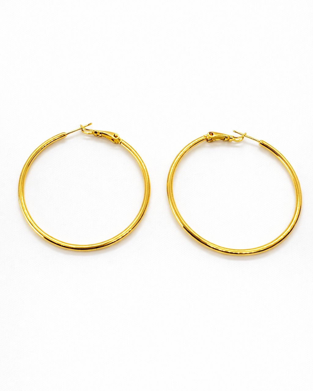 80s inspired thin gold hoop earrings stainless steel 1.8 inch latch lock hoops on white background