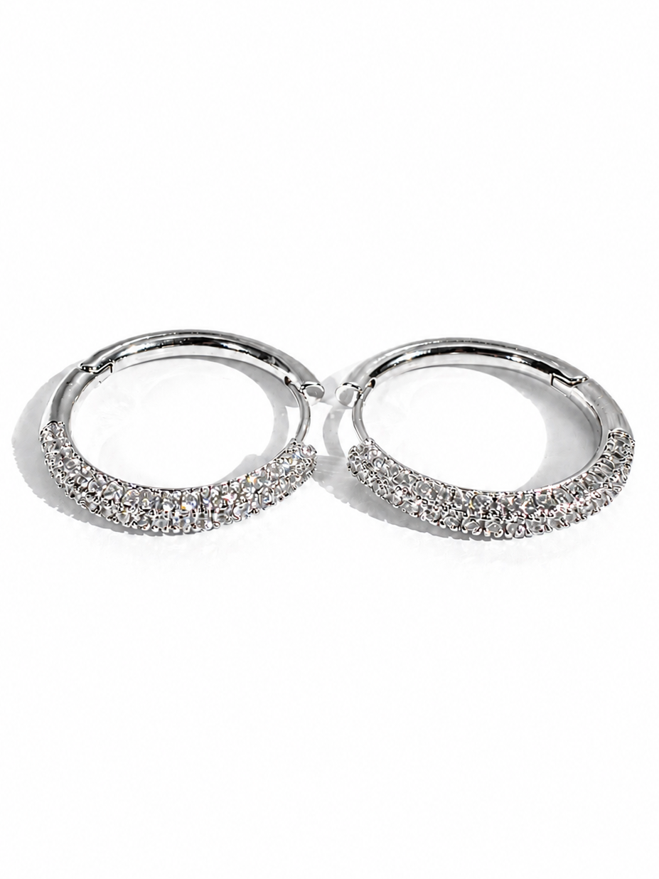 Pair of silver hoop earrings with embedded stones on a white background