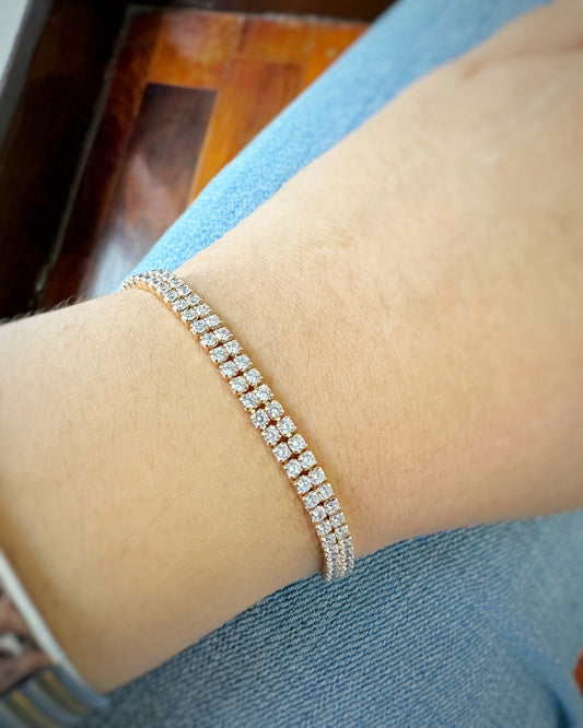Close-up of two-row tennis bracelet worn on wrist, paired with denim