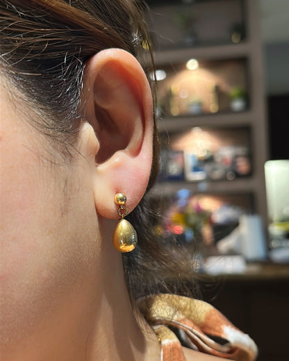 Close-up of an ear wearing a gold earring with a blurred background