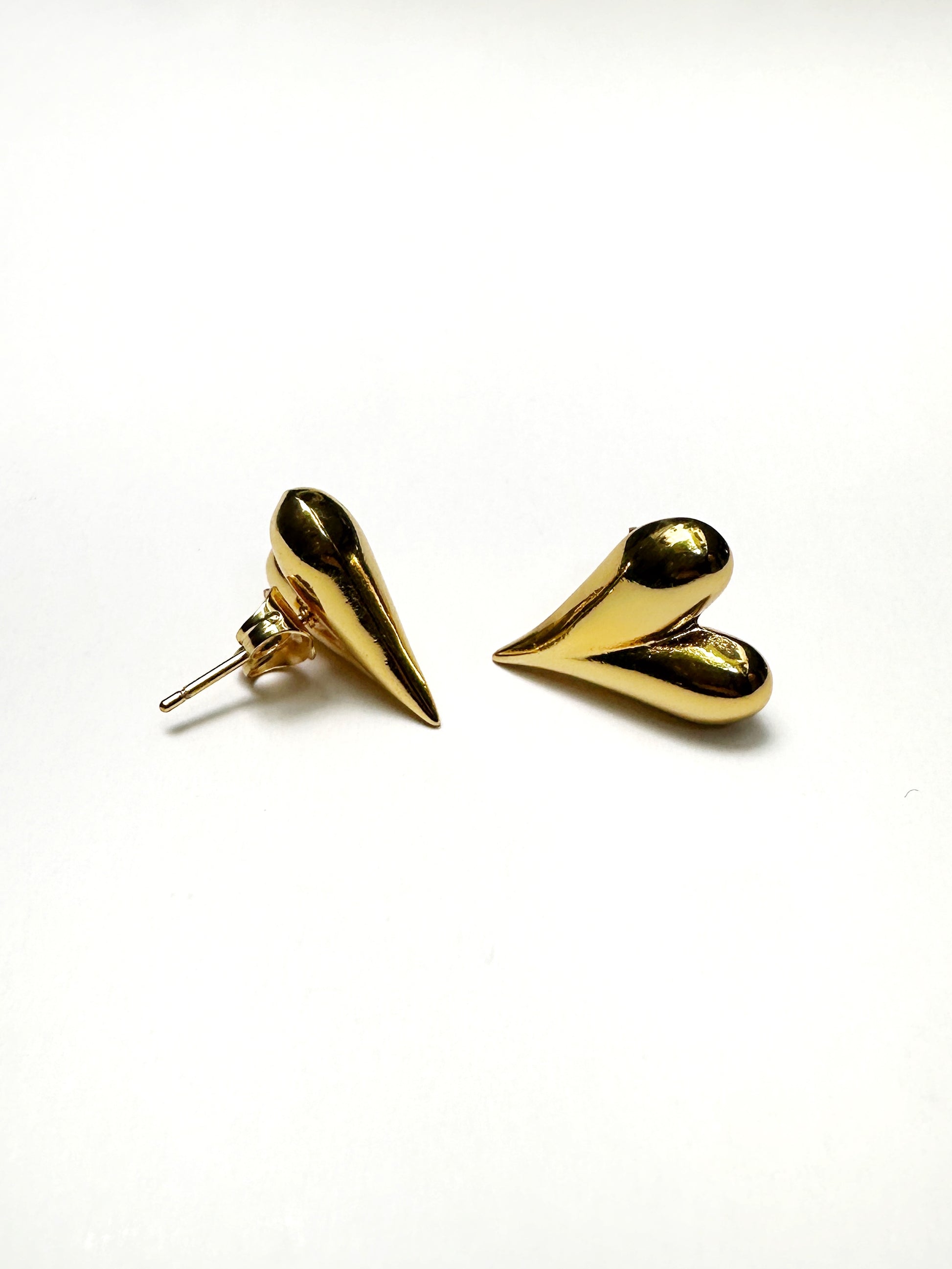 Angled view of gold puff heart earrings highlighting curved design