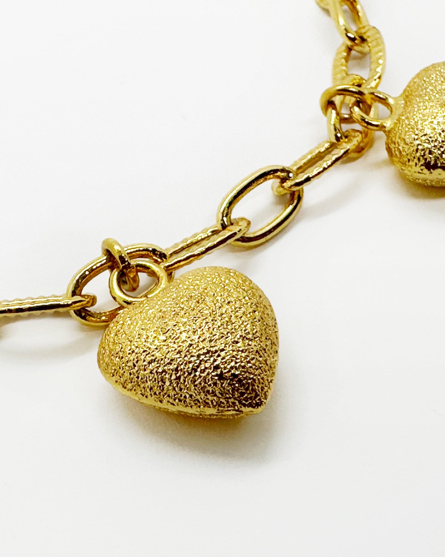 Detailed view of frosted gold heart charm surface