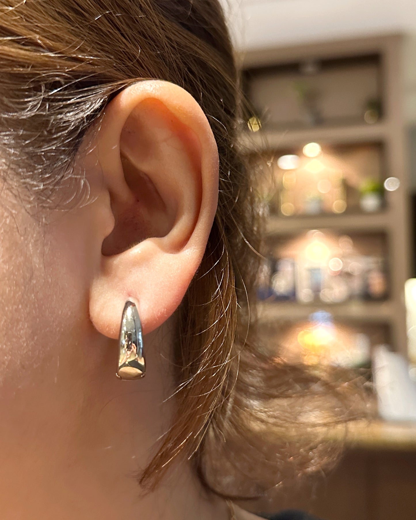 Cashew huggie earrings worn on ear showing close, comfortable fit