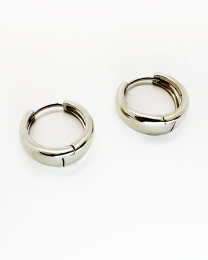 Angled view of cashew-shaped huggie earrings with polished white gold shine