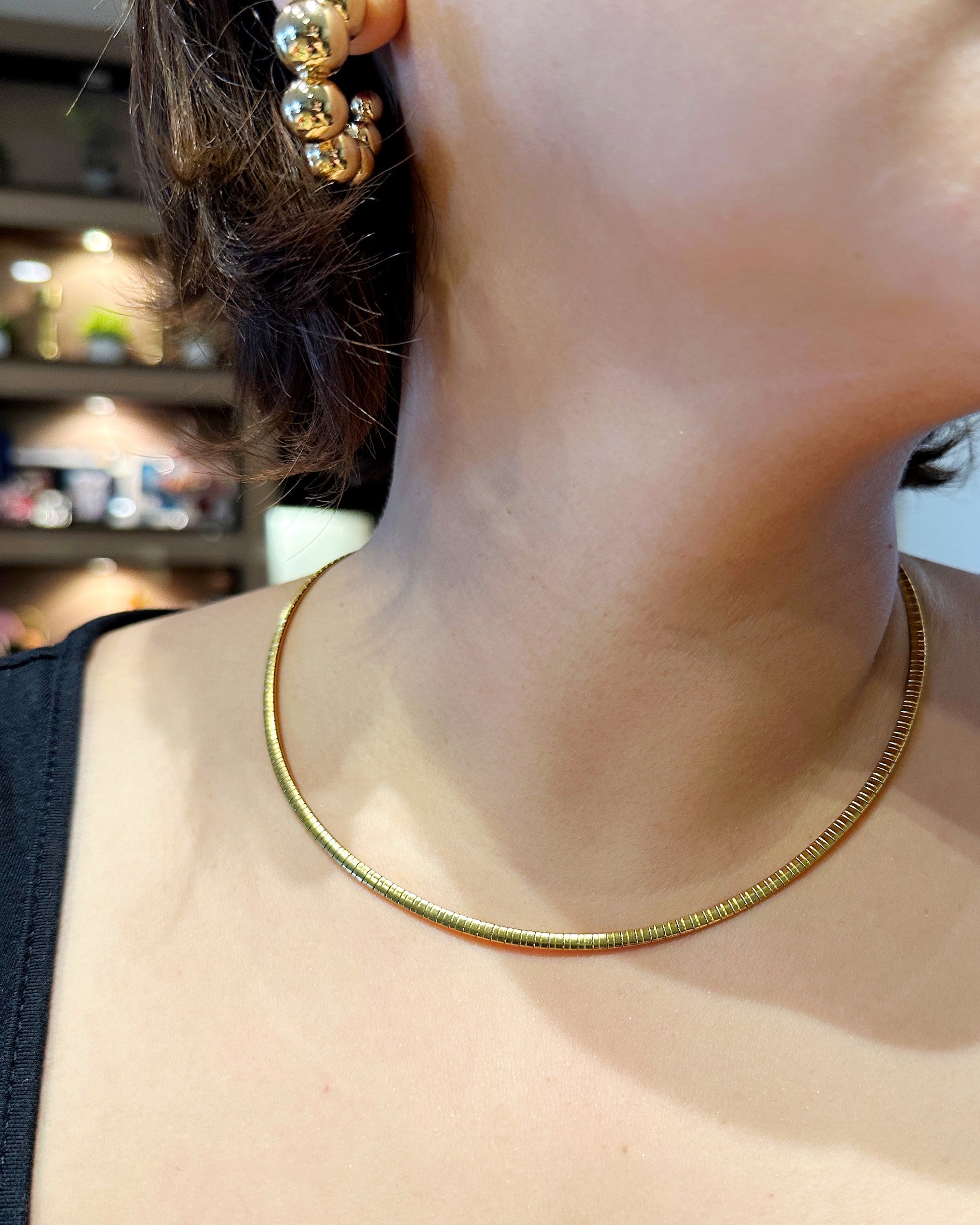 Sleek gold necklace worn around neck, perfect for layering or solo wear