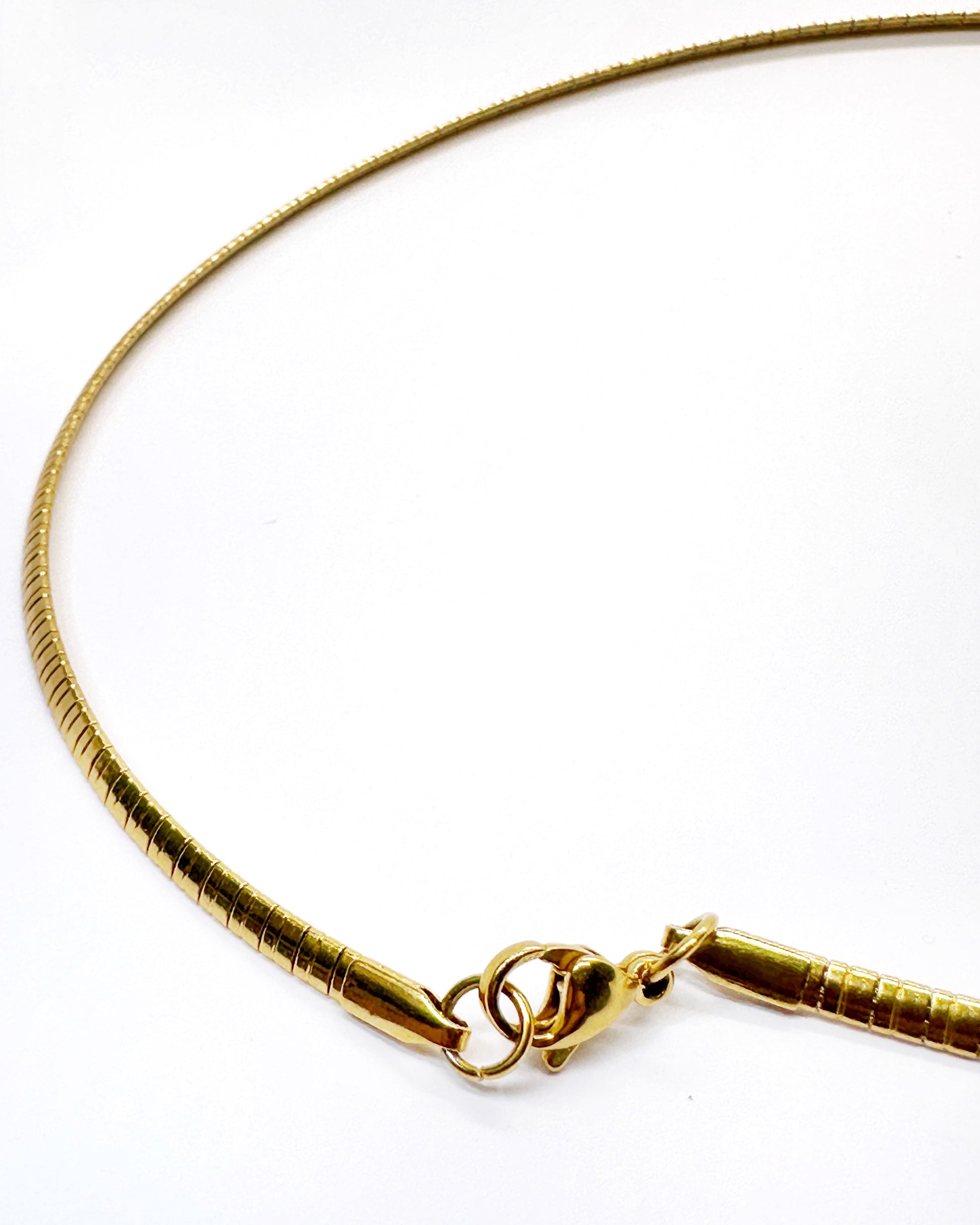 Minimalist gold snake chain necklace detail highlighting flexibility
