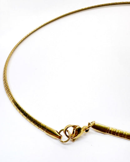 Minimalist gold snake chain necklace detail highlighting flexibility