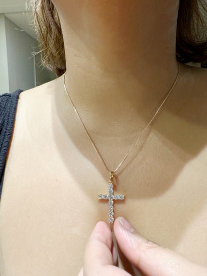 Zirconia cross pendant necklace worn on model held by hand, 18-inch chain