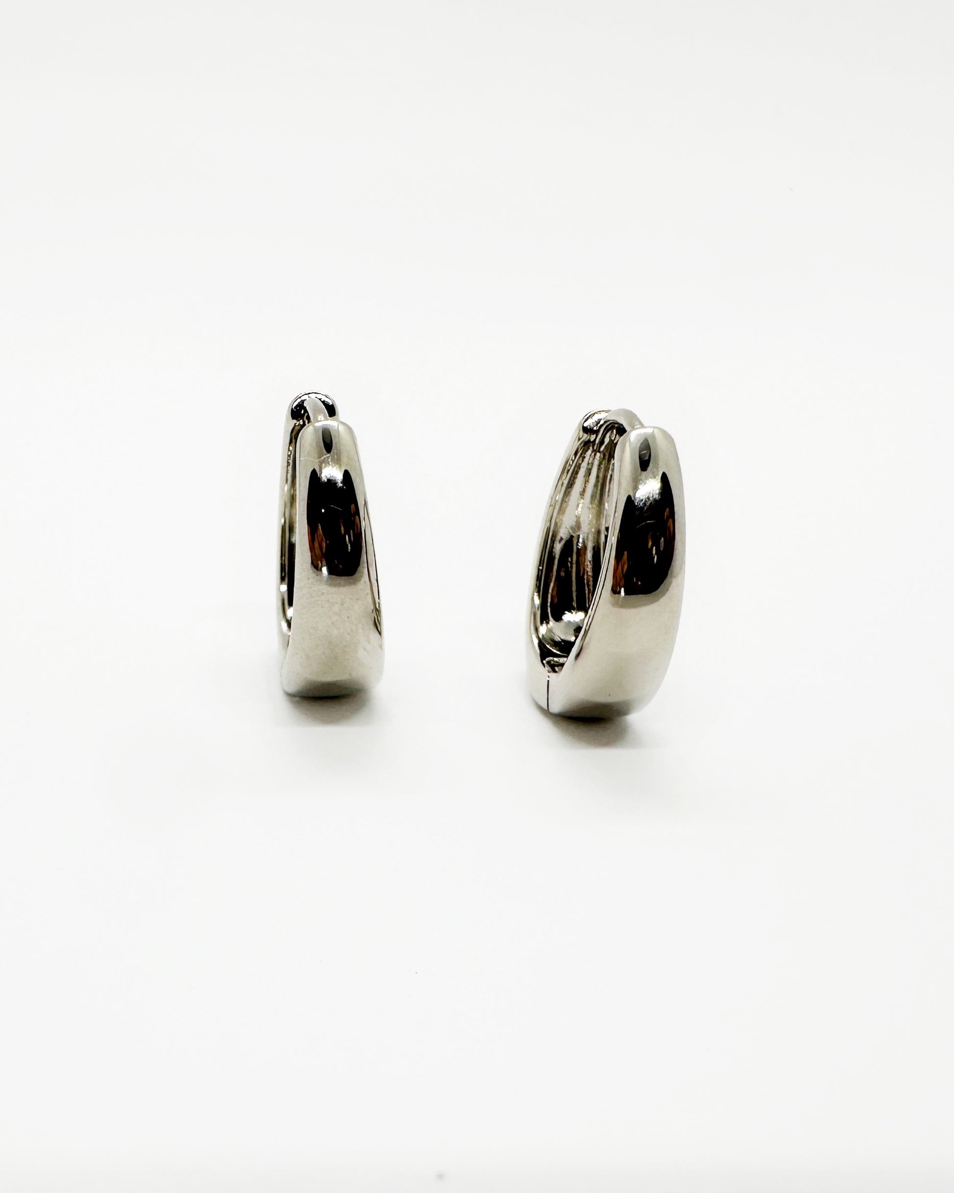 Side profile of curved cashew huggie earrings in 18K white gold dipping