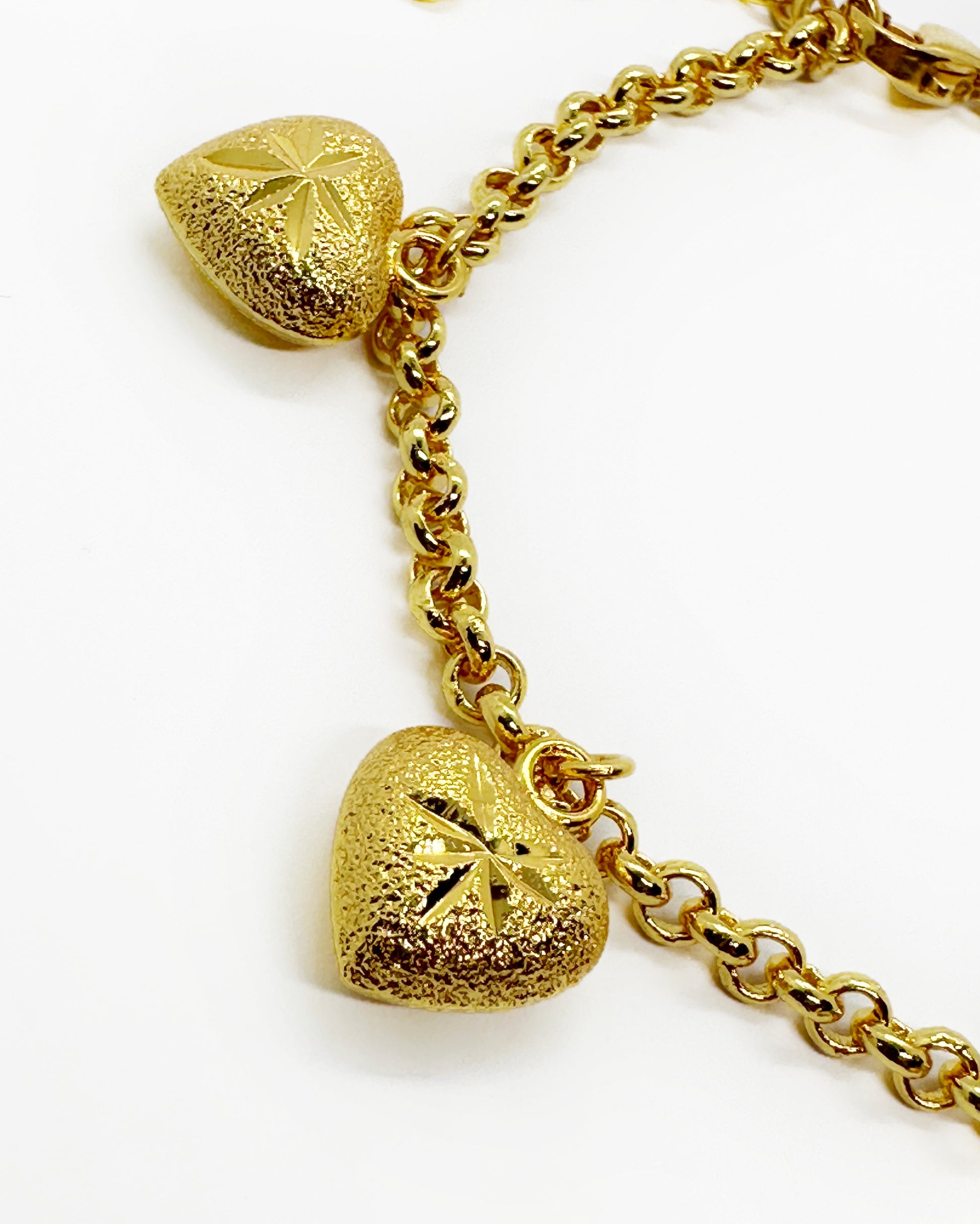 Close-up of frosted heart charm with engraved detail and matte gold texture