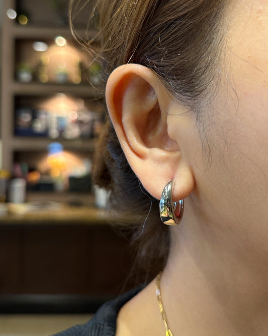 Minimal silver-tone cashew huggie hoop earrings styled for everyday wear